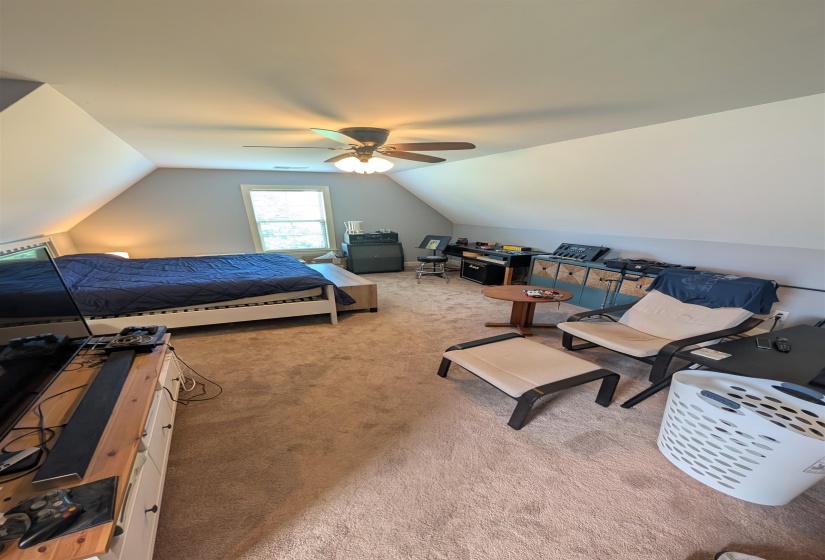 Carpeted room with vaulted ceilings and a ceiling fan with integrated lighting