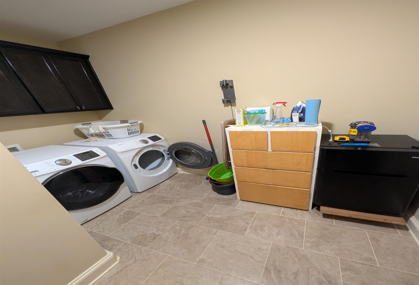Laundry area with tile flooring and built-in dark cabinetry