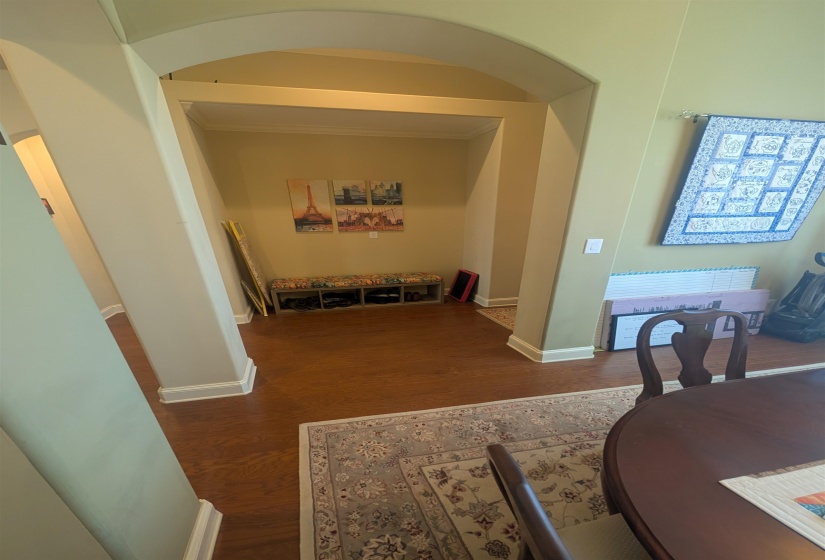 Archway entry with wood-finish flooring, light-toned walls, and white baseboards