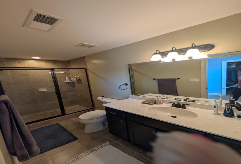 Bathroom featuring a dark wood-finish vanity with a light-colored countertop, an oval undermount sink, and a black faucet