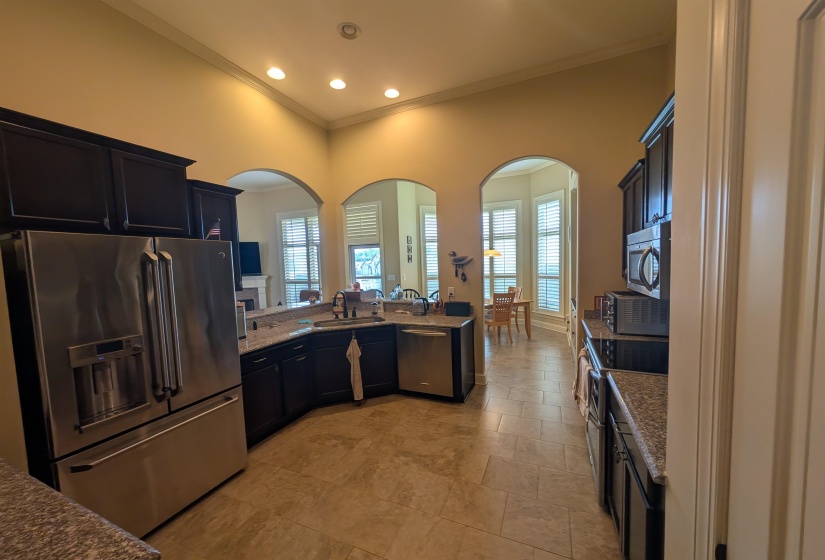 Gourmet kitchen featuring dark wood cabinetry, stainless steel appliances, and stone countertops