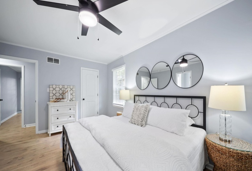 Bedroom featuring wood-finish flooring, a ceiling fan with integrated lighting, white trim, and a window with blinds