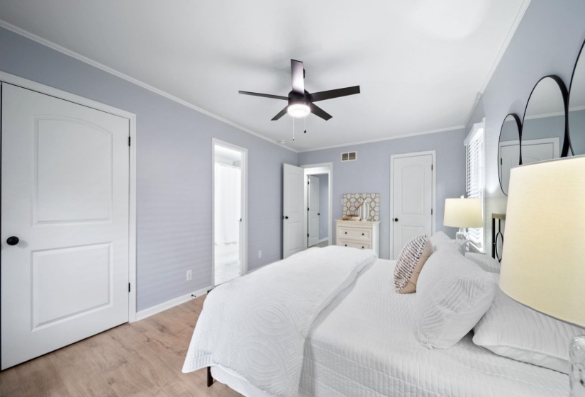 Bedroom featuring wood-finish flooring, light blue walls, a ceiling fan with integrated lighting, and white trim