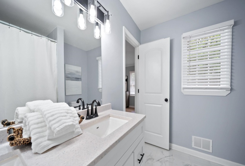 Bathroom featuring a single vanity with stone-finish countertop, undermount sink, and dark-finish faucet