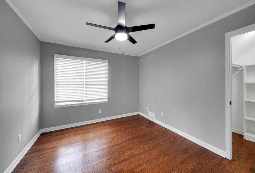 Empty room featuring a ceiling fan, wood finished floors, and ornamental molding