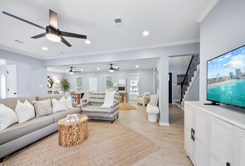 Spacious living area featuring light wood-finish flooring, recessed lighting, and ceiling fans