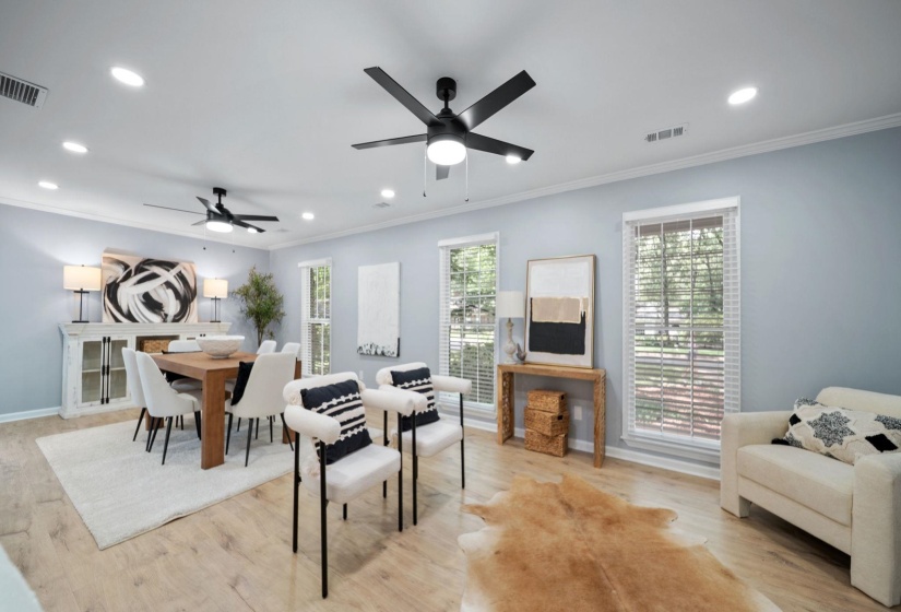 Open-concept living space featuring wood-finish flooring, recessed lighting, and multiple large windows with white blinds