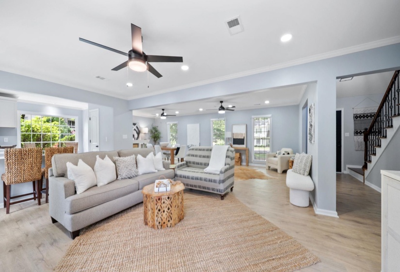 Expansive open-concept living space with light-toned wood-finish flooring, recessed lighting, and a contemporary ceiling fan
