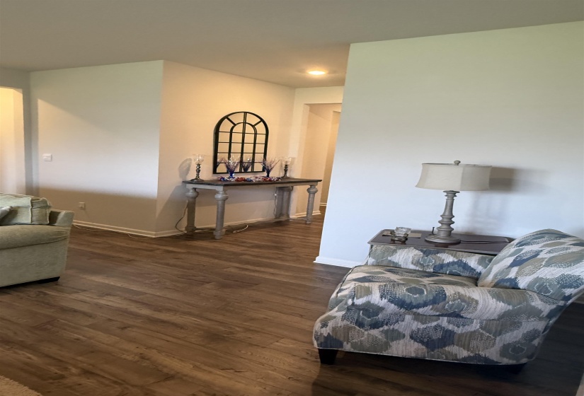 Warm wood-finish flooring extending throughout the space, complemented by crisp white baseboards and neutral wall tones