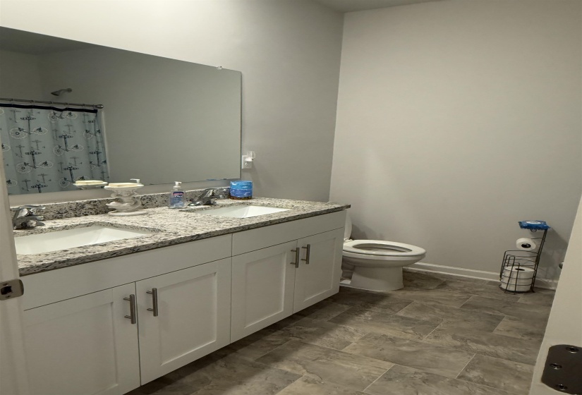 Double vanity with white cabinetry, integrated sinks, and a stone-finish countertop