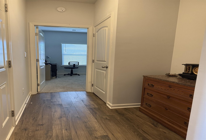Hallway featuring wood-finish flooring, light gray wall paint, and white trim molding