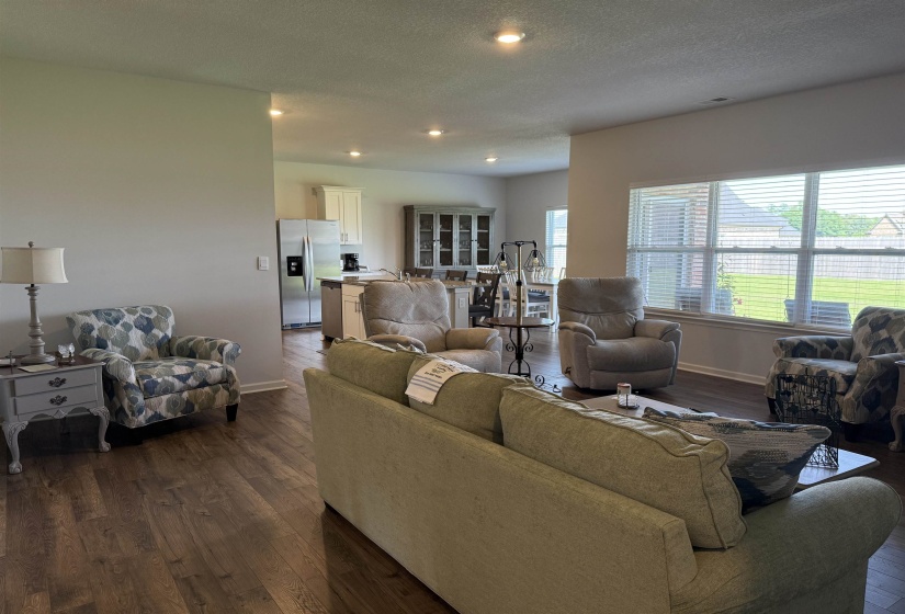 Open-concept living area featuring wood-finish flooring, recessed lighting, and ample natural light through large windows