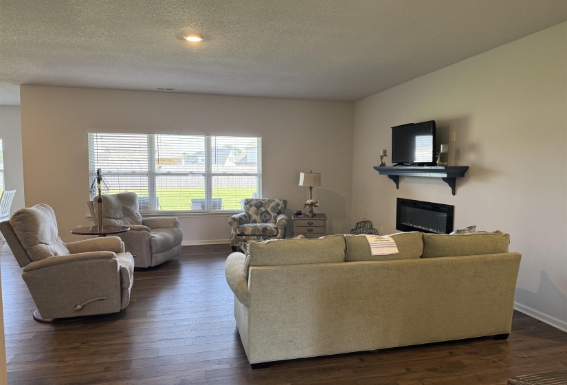 Spacious living area featuring wood-finish flooring, recessed lighting, and a built-in electric fireplace