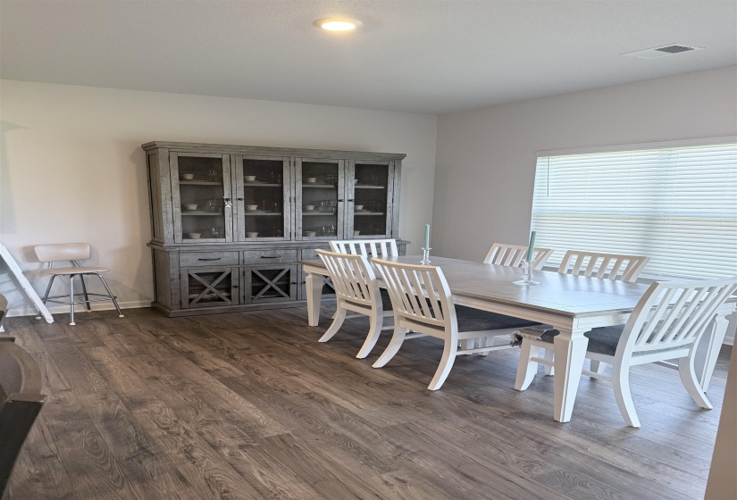 Spacious dining area featuring wood-finish flooring, recessed lighting, and a large window with blinds