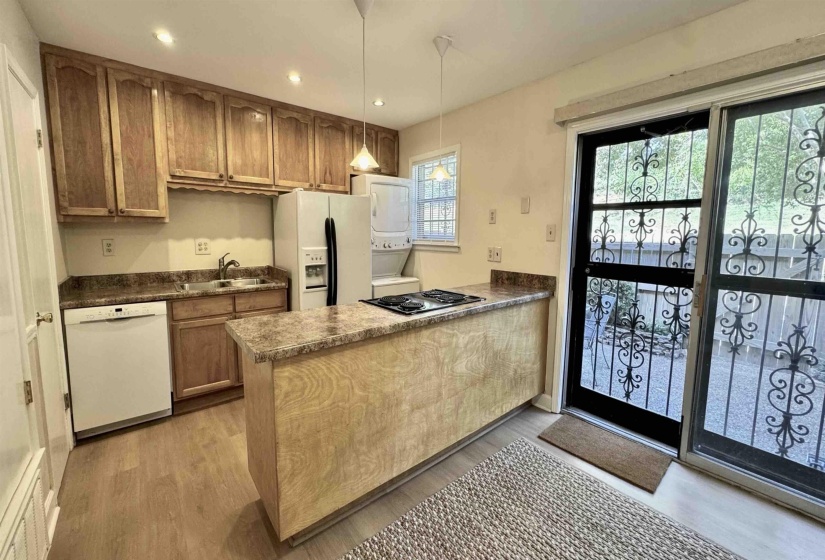 Kitchen featuring a peninsula, recessed lighting, white appliances, decorative light fixtures, and light wood-style floors