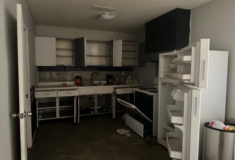 Kitchen featuring decorative backsplash, sink, dark tile patterned flooring, a textured ceiling, and white appliances