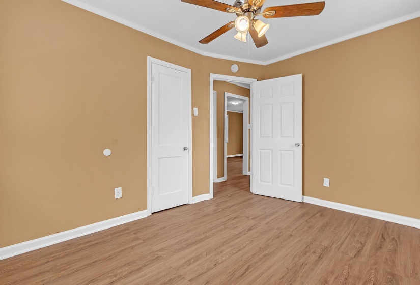 Room featuring wood-finish flooring, warm-toned walls, white trim, and a ceiling fan with integrated lighting