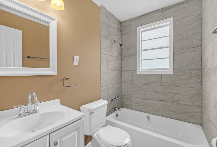 Bathroom featuring a white vanity with integrated sink, chrome faucet, and a framed mirror