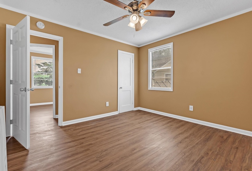 Interior room featuring wood-finish flooring, a single window, and a ceiling fan with integrated lighting