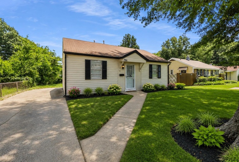 Cream-colored siding facade featuring black window shutters and a brown shingle roof
