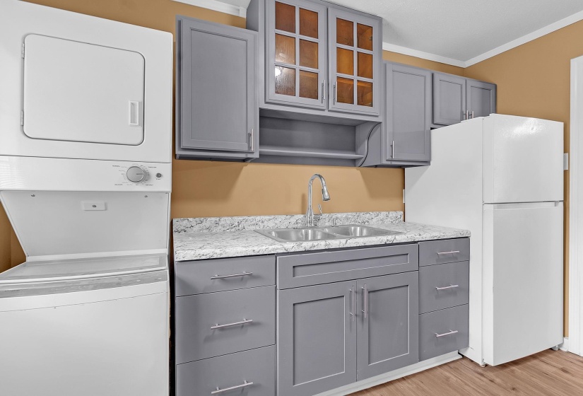 Kitchenette featuring gray shaker-style cabinetry with chrome hardware, a double basin stainless steel sink with a high-arc faucet, and granite-look countertops