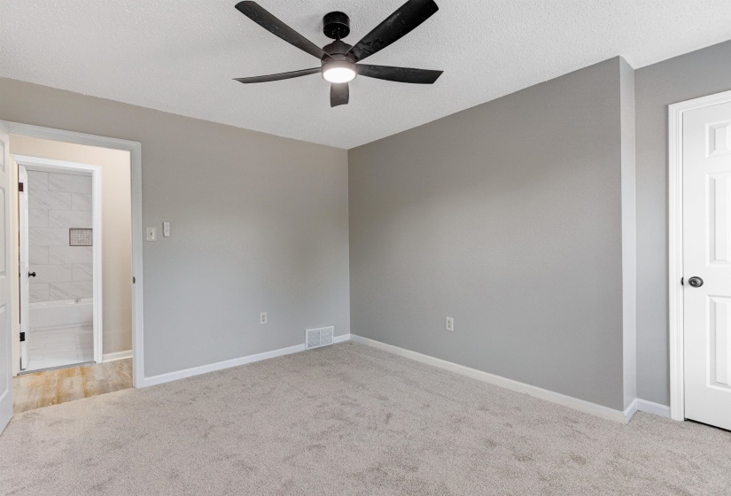 Unfurnished bedroom featuring light carpet, a textured ceiling, and ceiling fan