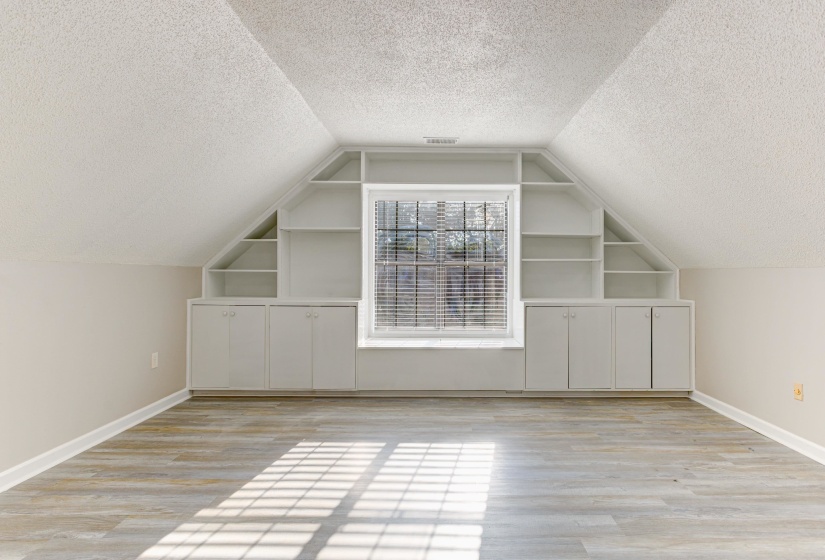 Bonus room with a textured ceiling, light wood-style floors, vaulted ceiling, and built in features