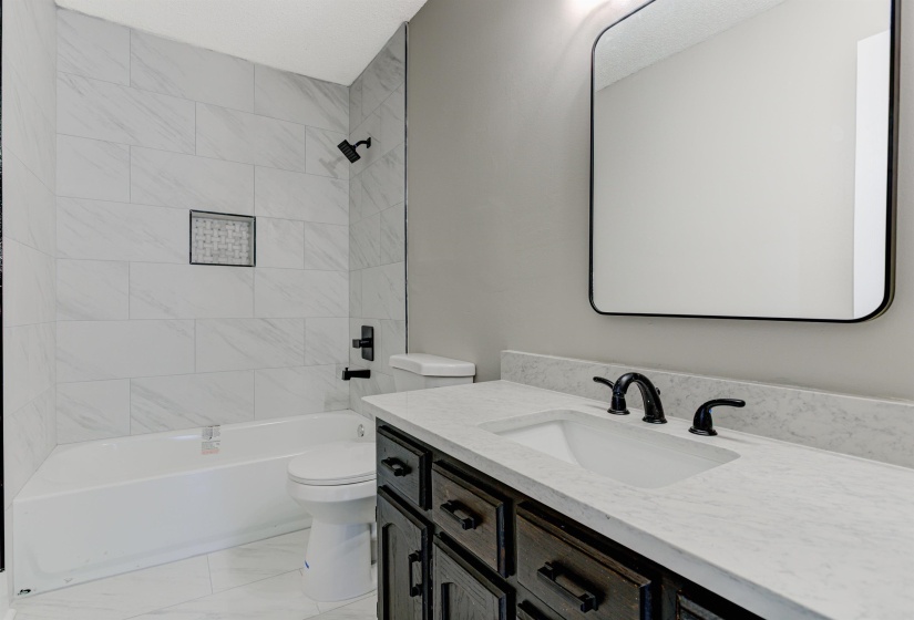 Bathroom featuring tub / shower combination, vanity, and light marble finish flooring