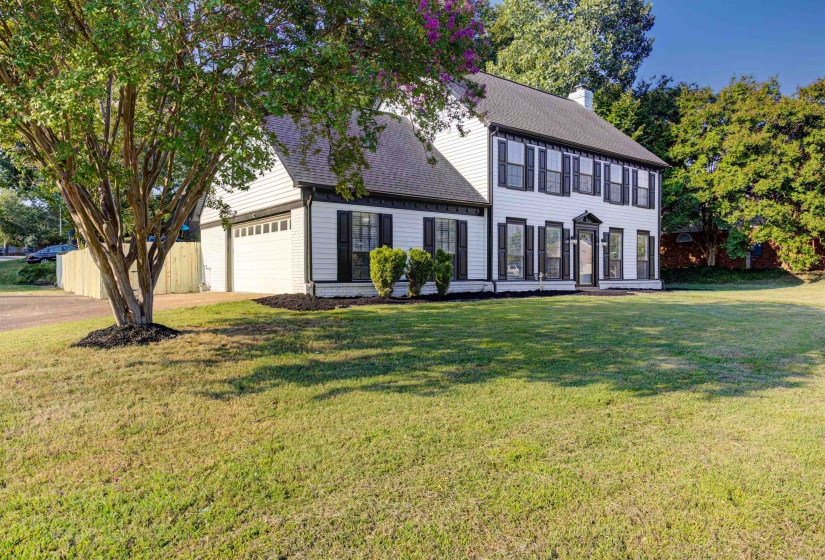 Colonial house with roof with shingles, a chimney, a front yard, a garage, and driveway