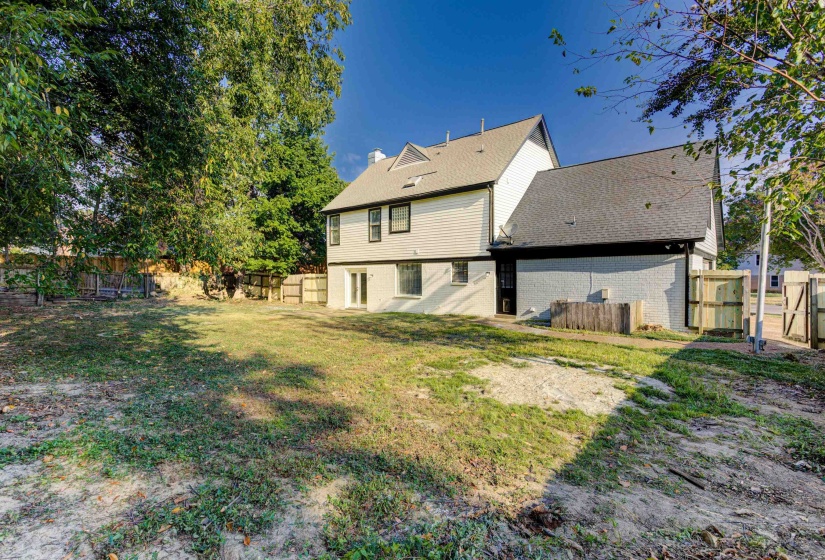 Back of house featuring a fenced backyard, brick siding, a chimney, and roof with shingles
