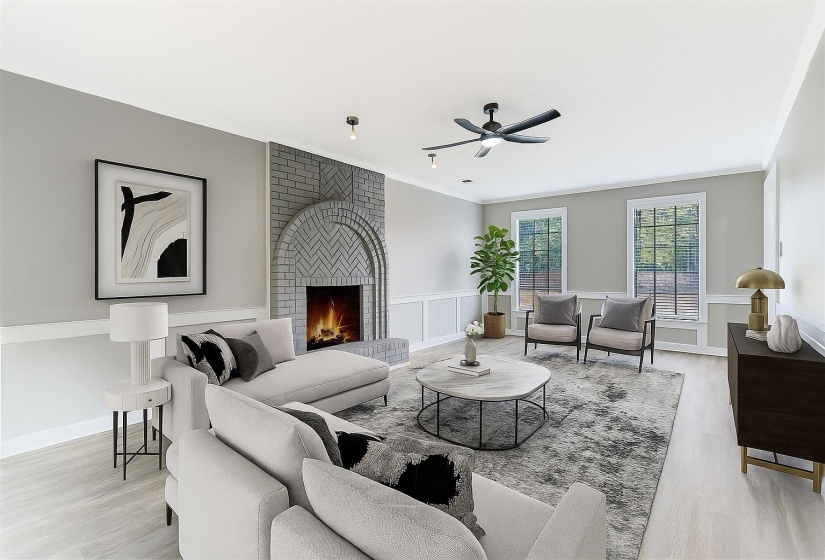 Living area featuring light wood-style flooring, a fireplace, ceiling fan, crown molding, and a wainscoted wall