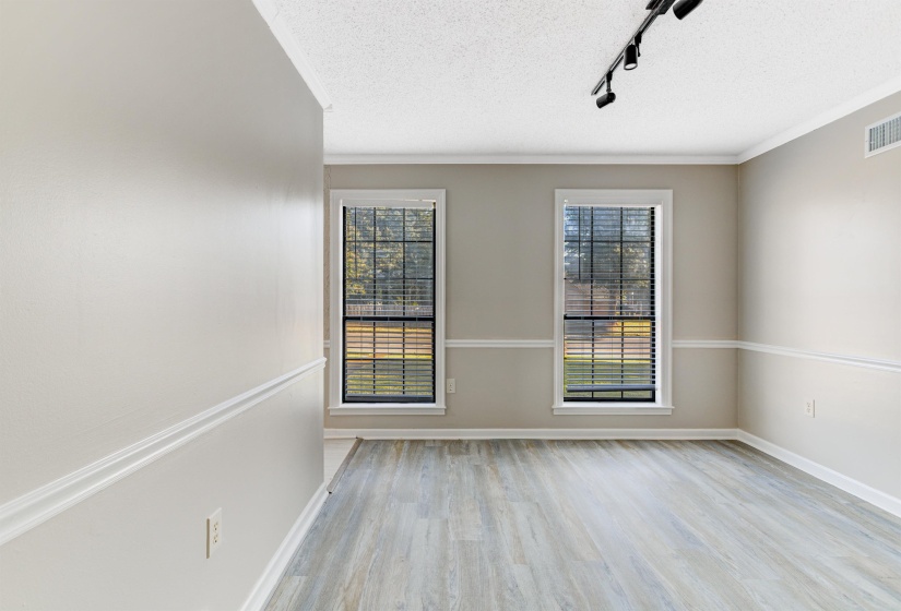 Spare room with rail lighting, light wood-style flooring, a textured ceiling, and ornamental molding