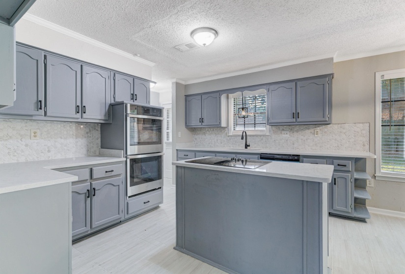 Kitchen with a center island, gray cabinetry, tasteful backsplash, a textured ceiling, and stainless steel appliances