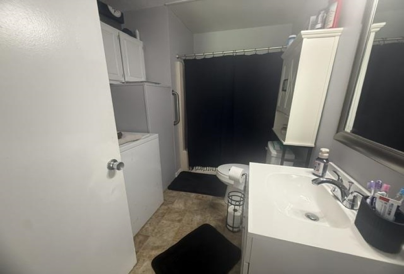 Compact bathroom featuring an integrated sink vanity, wall-mounted storage cabinet, and a built-in shower with a grab bar