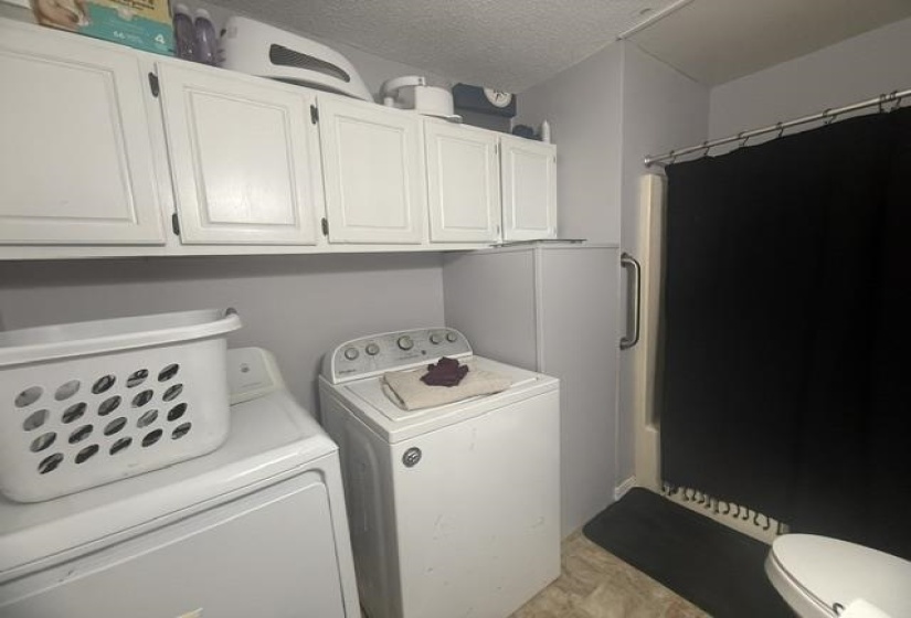 White cabinetry over a laundry area featuring a washer and dryer setup