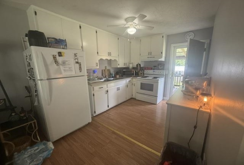 Kitchen featuring wood-finish flooring, white cabinetry, and white appliances