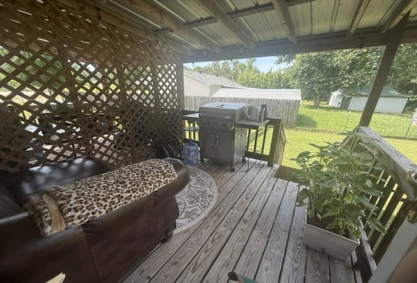 Covered outdoor deck featuring natural wood-finish flooring, a lattice privacy screen, and a metal roof