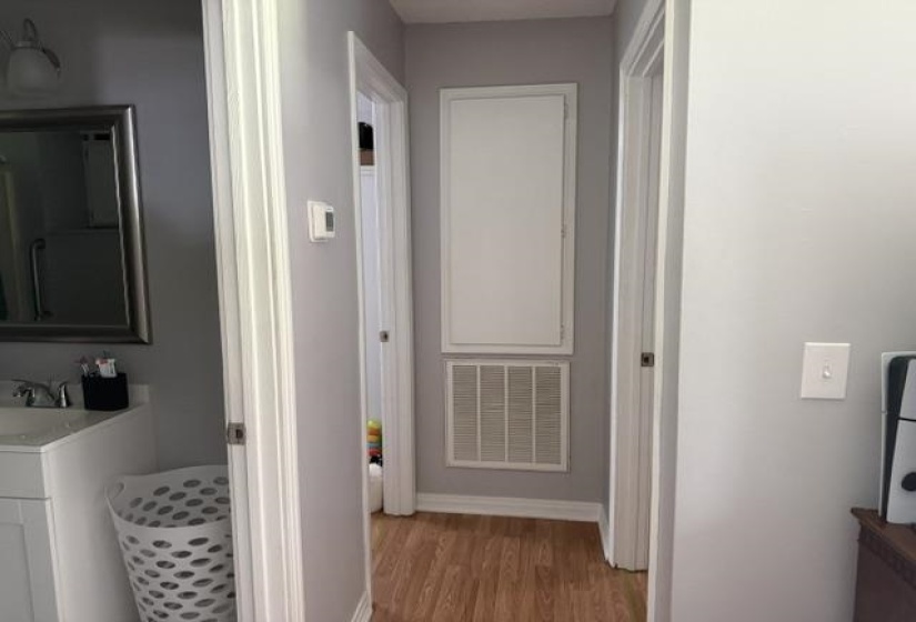 Hallway featuring wood-finish flooring, light gray wall paint, and white trim