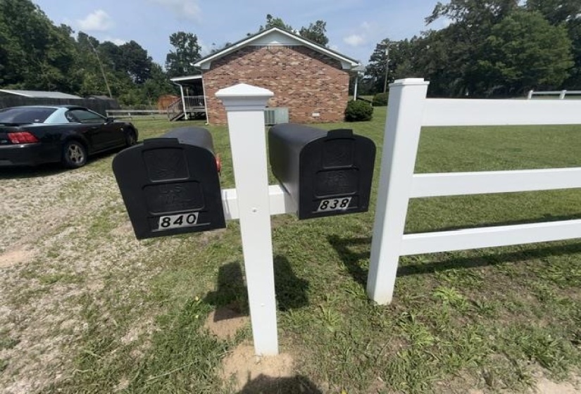 White split-rail fence alongside a post with two black mailboxes