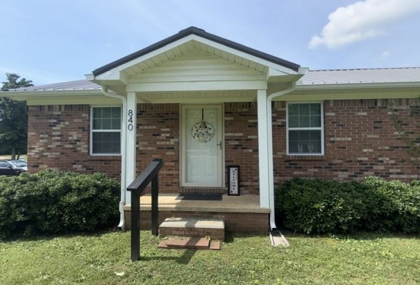 Brick exterior with a covered porch and a metal roof