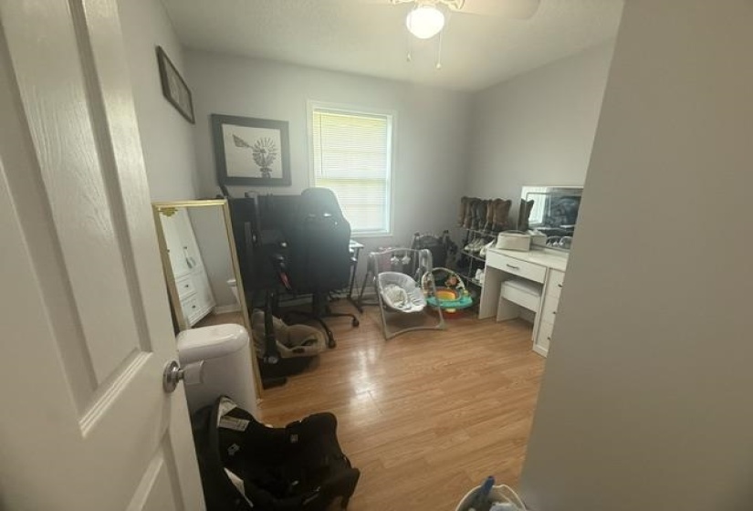 Room featuring light wood-finish flooring, a single window with blinds, a ceiling fan with integrated lighting, and neutral wall paint
