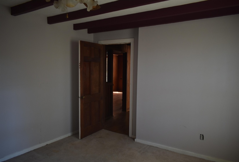 Unfurnished room with light carpet, beamed ceiling, and a ceiling fan