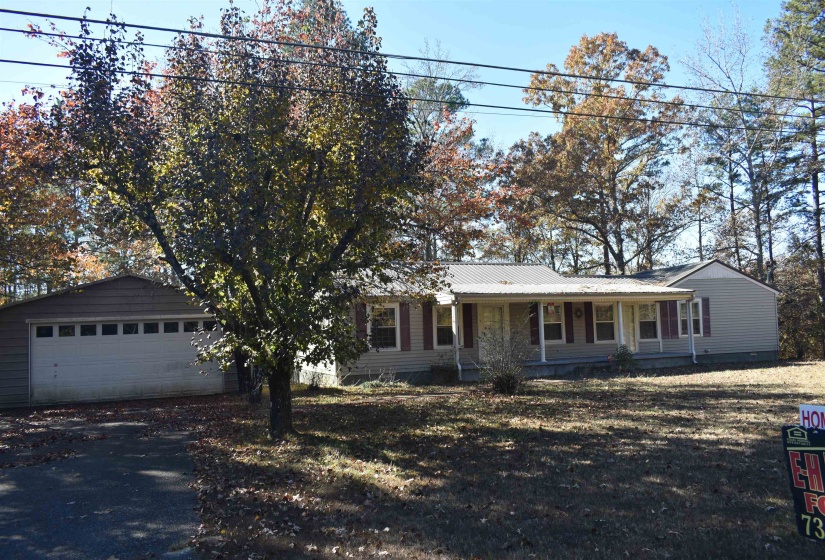Ranch-style house with a porch, a garage, and a metal roof