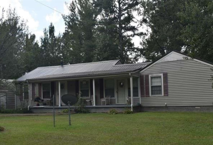 View of front of house with a porch, a front lawn, and a metal roof