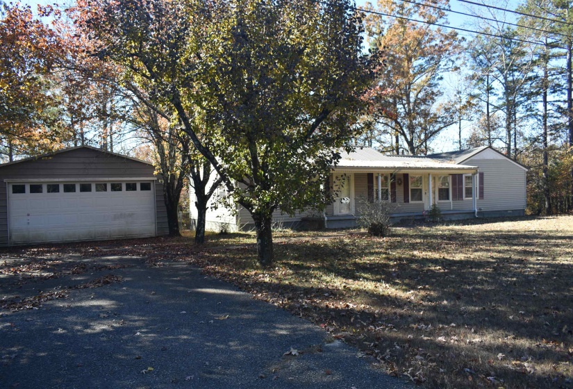 Single story home with covered porch, an outdoor structure, a metal roof, and a detached garage