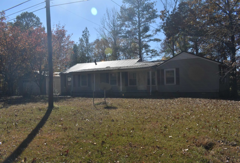 Back of property featuring a lawn and a metal roof