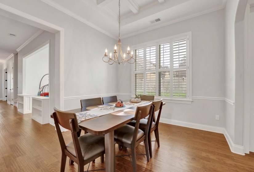 Dining space featuring wood-finish flooring, a coffered ceiling, and a chandelier