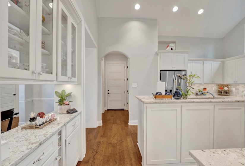 Kitchen featuring white cabinetry, granite countertops, wood-finish flooring, recessed lighting, and a neutral tile backsplash