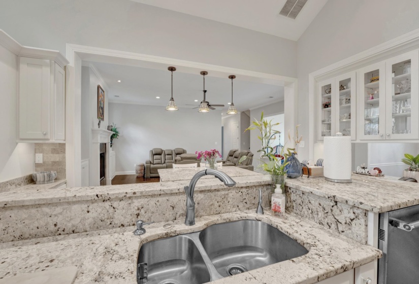 Kitchen featuring white cabinetry, light-toned stone countertops, a double basin stainless steel sink, and a stone tile backsplash