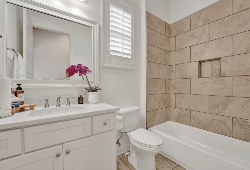 Bathroom featuring a built-in tub with large format tile surround and recessed shelving